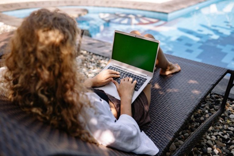 O femeie cu laptopul deschis stă lângă un copil care își scrie temele la birou